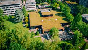 Luftaufnahme eines Gebäudes mit grünem Dach in einem baumreichen Gebiet