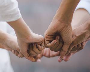 Sechs Personen geben sich in einem Kreis gegenseitig die Faust