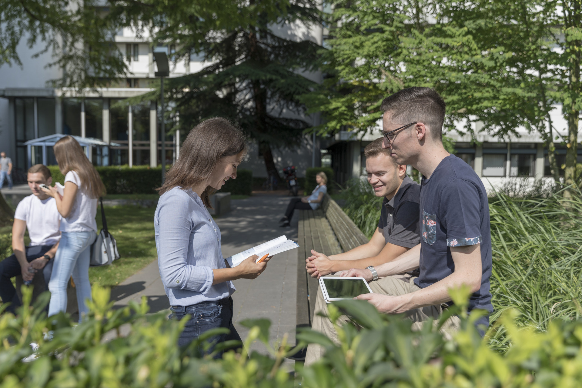 Gruppen stehen zusammen auf dem Campus vor Internat.